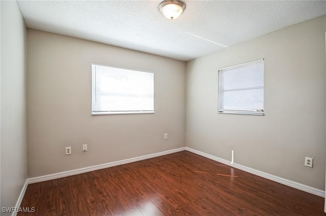 unfurnished room featuring dark wood-type flooring, a textured ceiling, and a wealth of natural light