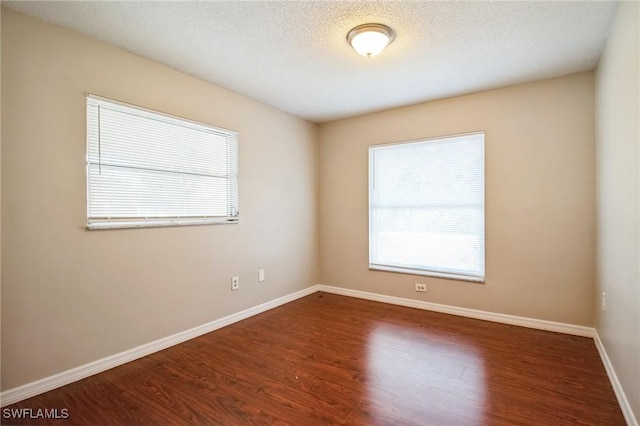 unfurnished room featuring wood-type flooring, a healthy amount of sunlight, and a textured ceiling