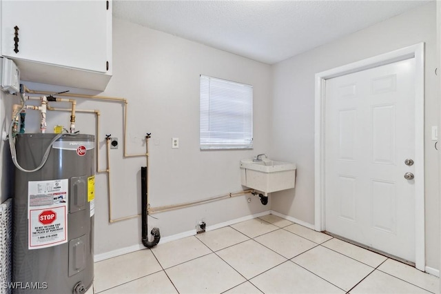 laundry area featuring light tile patterned floors, cabinets, electric water heater, and a textured ceiling