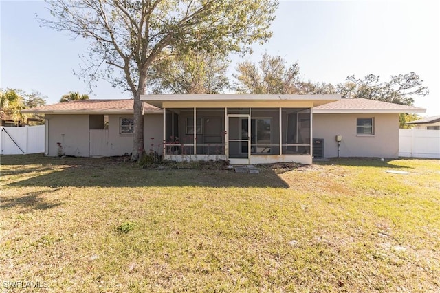 rear view of property featuring central AC unit, a sunroom, and a lawn