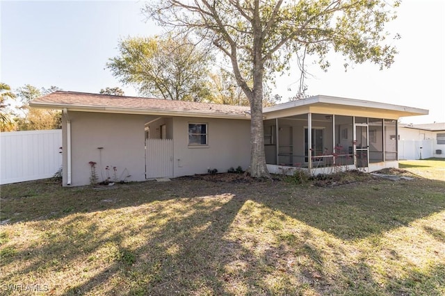 rear view of property featuring a yard and a sunroom