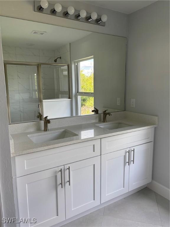 bathroom featuring tile patterned flooring, vanity, and walk in shower