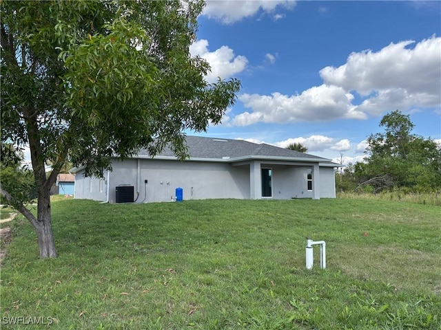 rear view of house featuring a yard and central air condition unit