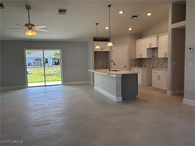 kitchen featuring an island with sink, sink, white cabinets, and decorative backsplash