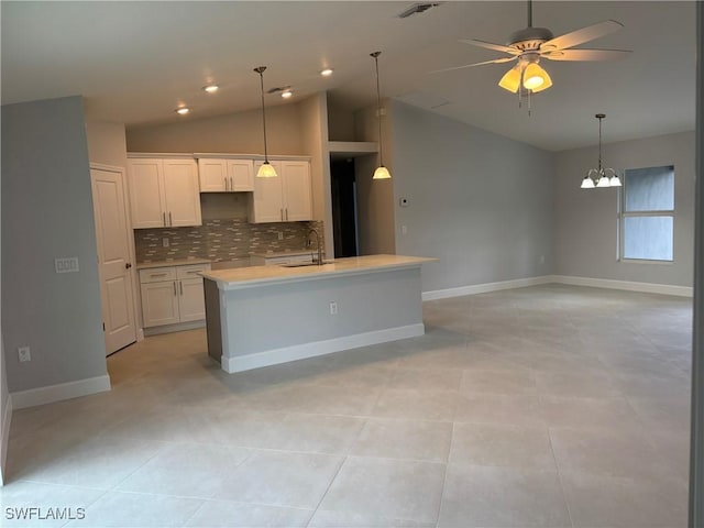 kitchen with ceiling fan with notable chandelier, sink, a center island with sink, and white cabinets