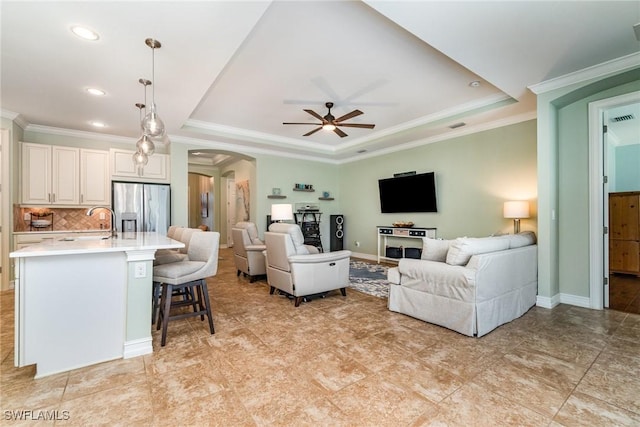 living room featuring a raised ceiling, crown molding, and ceiling fan