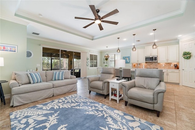 tiled living room with a raised ceiling, crown molding, and plenty of natural light