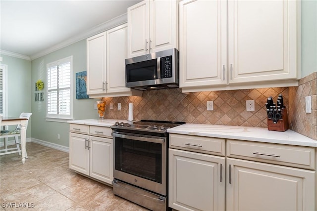 kitchen featuring light tile patterned floors, ornamental molding, appliances with stainless steel finishes, white cabinets, and backsplash