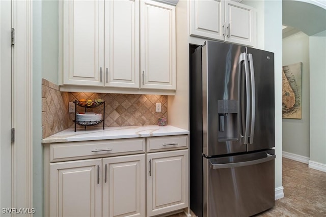 kitchen featuring white cabinets, stainless steel fridge, decorative backsplash, light tile patterned floors, and light stone counters