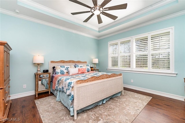 bedroom with hardwood / wood-style flooring, ornamental molding, ceiling fan, and a tray ceiling