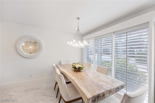 dining room with a notable chandelier, marble finish floor, and baseboards