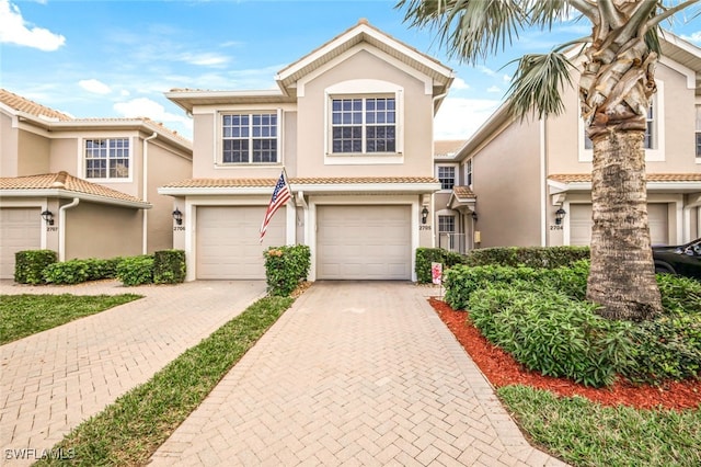 view of front of home with an attached garage, a tile roof, decorative driveway, and stucco siding