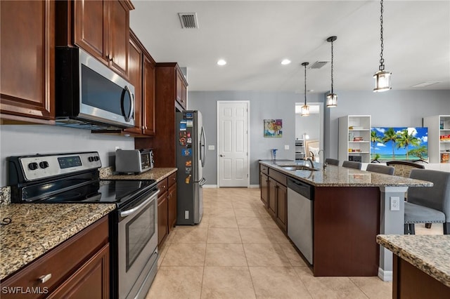 kitchen with visible vents, stainless steel appliances, a kitchen bar, a sink, and light tile patterned flooring