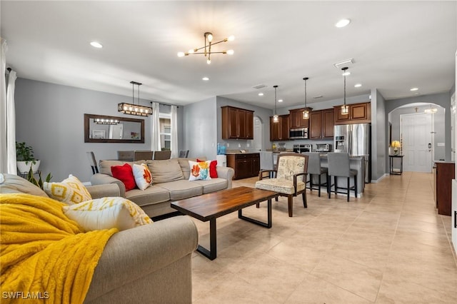 living room with arched walkways, a chandelier, and recessed lighting