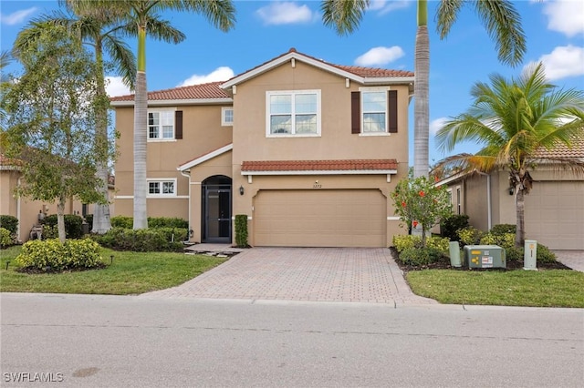 mediterranean / spanish home featuring a garage, decorative driveway, a tile roof, and stucco siding