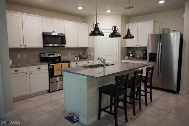 kitchen featuring sink, stone counters, white cabinetry, hanging light fixtures, and appliances with stainless steel finishes