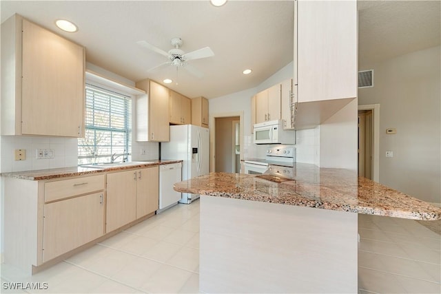 kitchen featuring lofted ceiling, sink, white appliances, light stone countertops, and kitchen peninsula