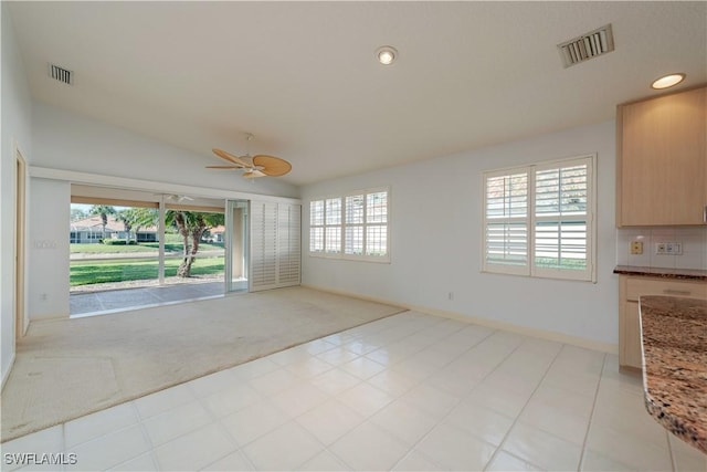 spare room featuring lofted ceiling, light colored carpet, and ceiling fan