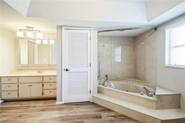 bathroom with hardwood / wood-style flooring, vanity, and a tub