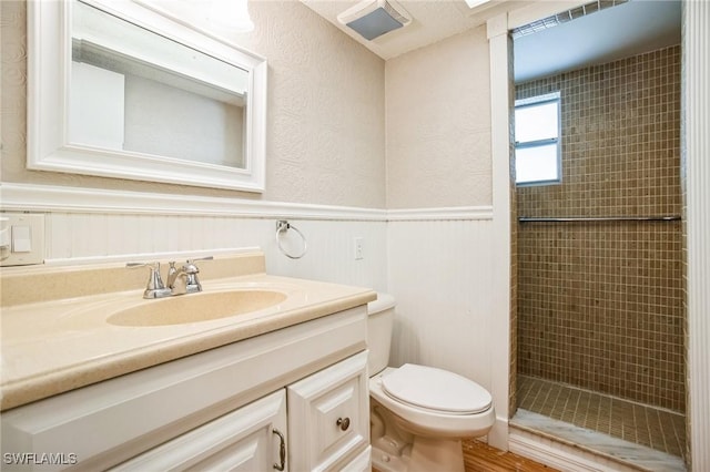 bathroom featuring vanity, tiled shower, and toilet