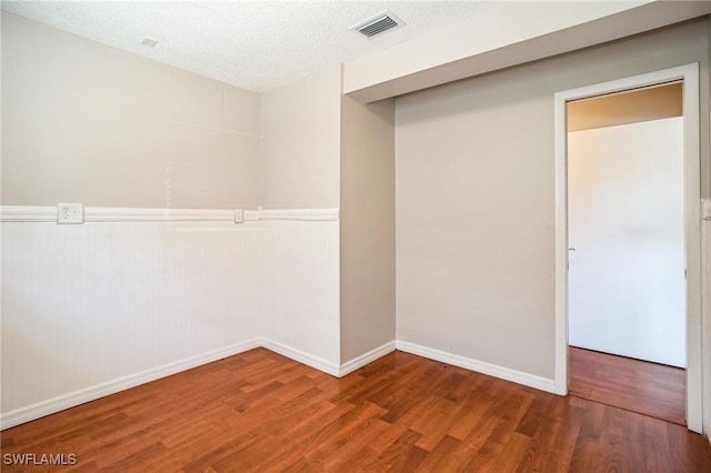 empty room with dark hardwood / wood-style floors and a textured ceiling