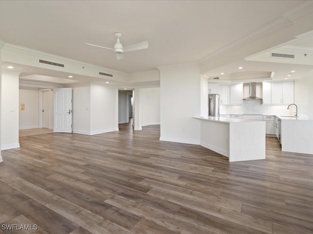 unfurnished living room with dark hardwood / wood-style flooring, sink, ornamental molding, and ceiling fan