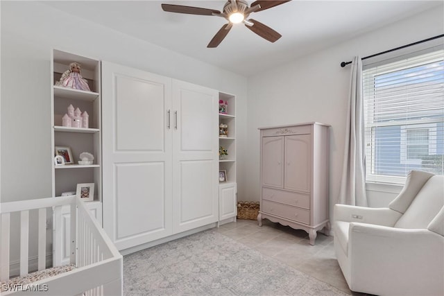 bedroom featuring light tile patterned flooring, multiple windows, a nursery area, and ceiling fan