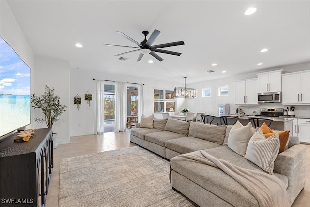 living room featuring ceiling fan with notable chandelier