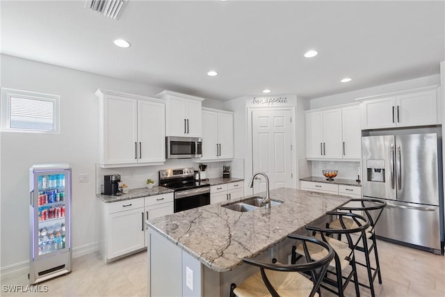 kitchen featuring sink, white cabinetry, stainless steel appliances, and an island with sink