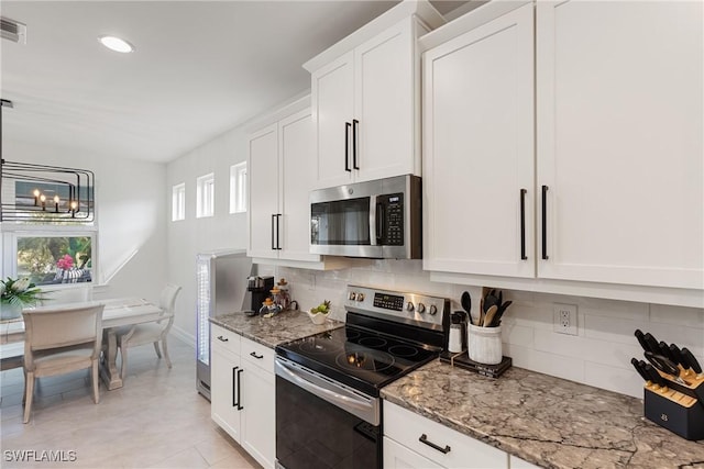 kitchen featuring white cabinetry, backsplash, appliances with stainless steel finishes, and light stone counters