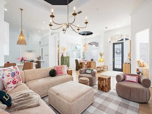 living room with light wood-type flooring, an inviting chandelier, and a tray ceiling