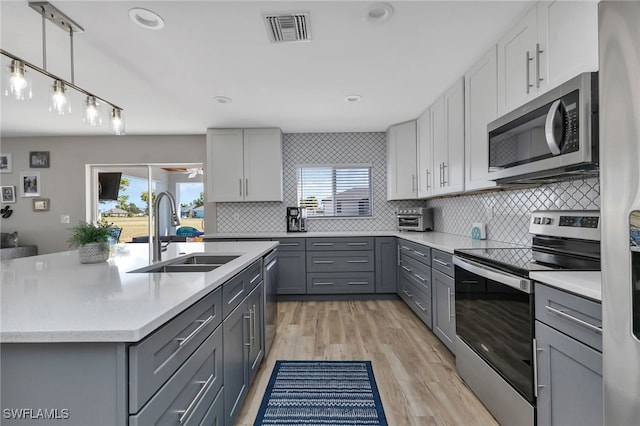 kitchen with gray cabinetry, sink, decorative backsplash, and appliances with stainless steel finishes