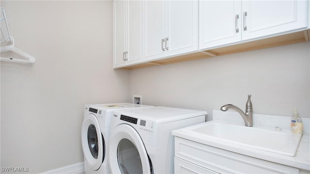 laundry area with independent washer and dryer, a sink, cabinet space, and baseboards