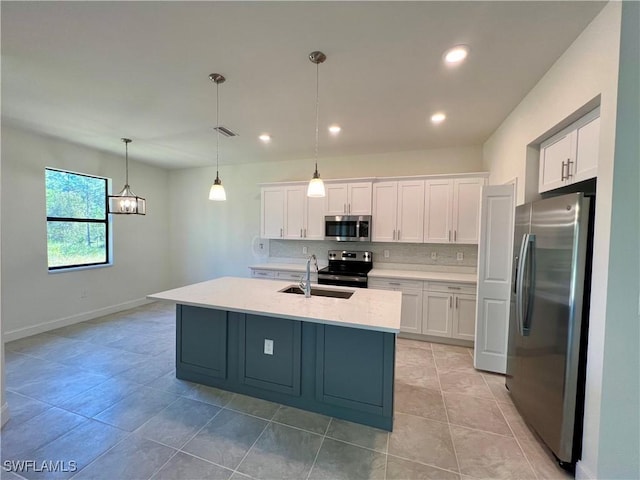 kitchen with appliances with stainless steel finishes, sink, pendant lighting, and white cabinets