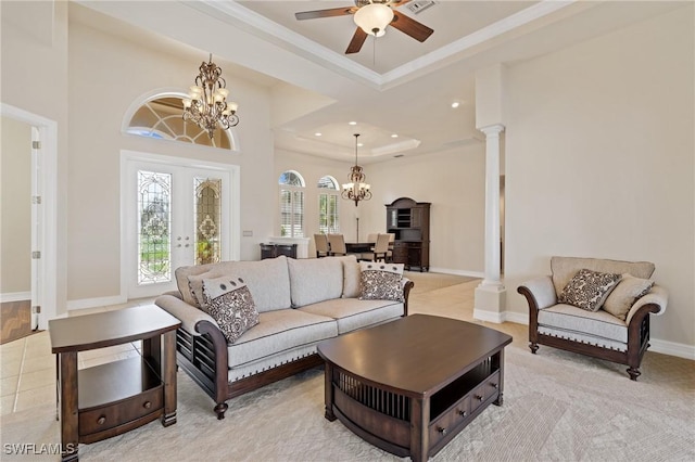 tiled living room with ceiling fan with notable chandelier, decorative columns, ornamental molding, a raised ceiling, and french doors