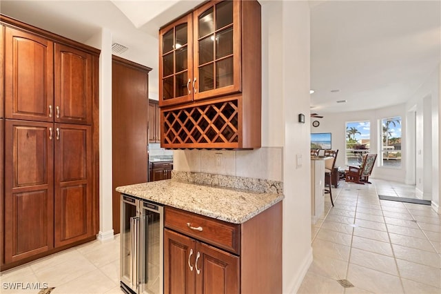 kitchen with light tile patterned flooring, beverage cooler, light stone countertops, and backsplash