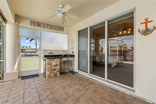 unfurnished sunroom featuring ceiling fan and sink