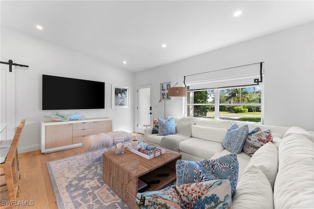 living room with a barn door and light wood-type flooring