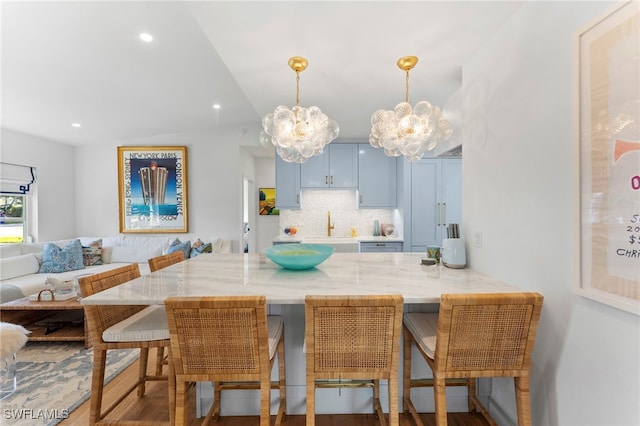 kitchen featuring decorative light fixtures, a kitchen bar, decorative backsplash, kitchen peninsula, and blue cabinetry