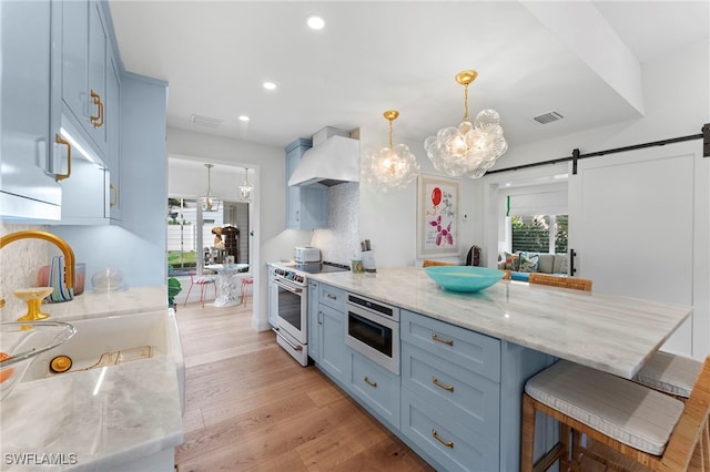 kitchen with a breakfast bar area, electric range oven, custom range hood, decorative light fixtures, and a barn door