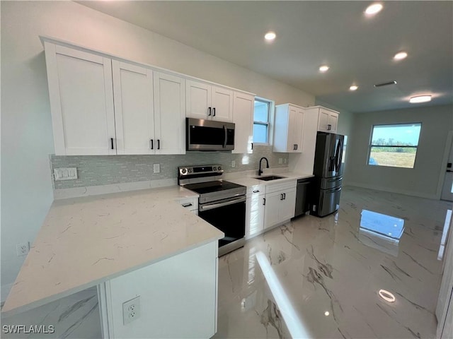 kitchen featuring sink, white cabinetry, backsplash, stainless steel appliances, and light stone counters