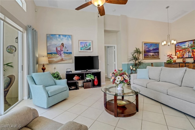 living room with a towering ceiling, ceiling fan with notable chandelier, and light tile patterned floors