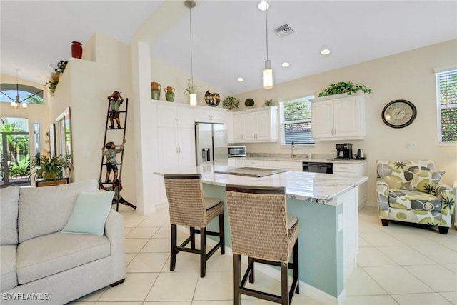 kitchen with a breakfast bar area, white cabinetry, black appliances, a kitchen island, and decorative light fixtures