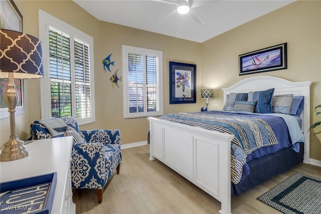 bedroom featuring ceiling fan, multiple windows, and light wood-type flooring