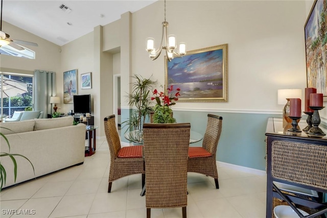 tiled dining space with ceiling fan with notable chandelier and high vaulted ceiling