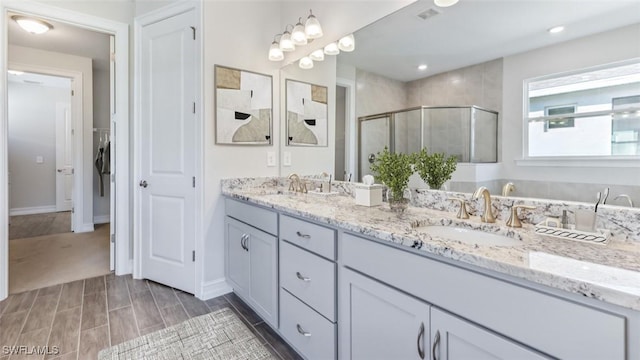 full bathroom with double vanity, a closet, a sink, and a shower stall