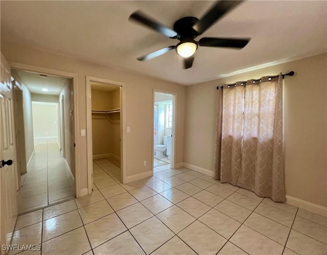 unfurnished bedroom featuring light tile patterned floors, ensuite bath, ceiling fan, a spacious closet, and a closet