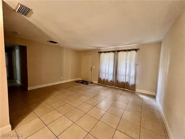 empty room with light tile patterned floors and a textured ceiling