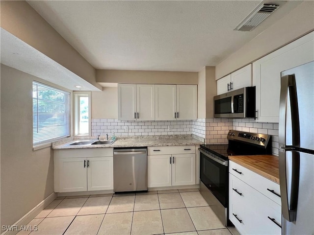 kitchen with tasteful backsplash, white cabinetry, appliances with stainless steel finishes, and sink