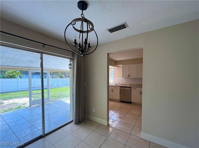 unfurnished dining area with a chandelier, sink, a textured ceiling, and light tile patterned floors